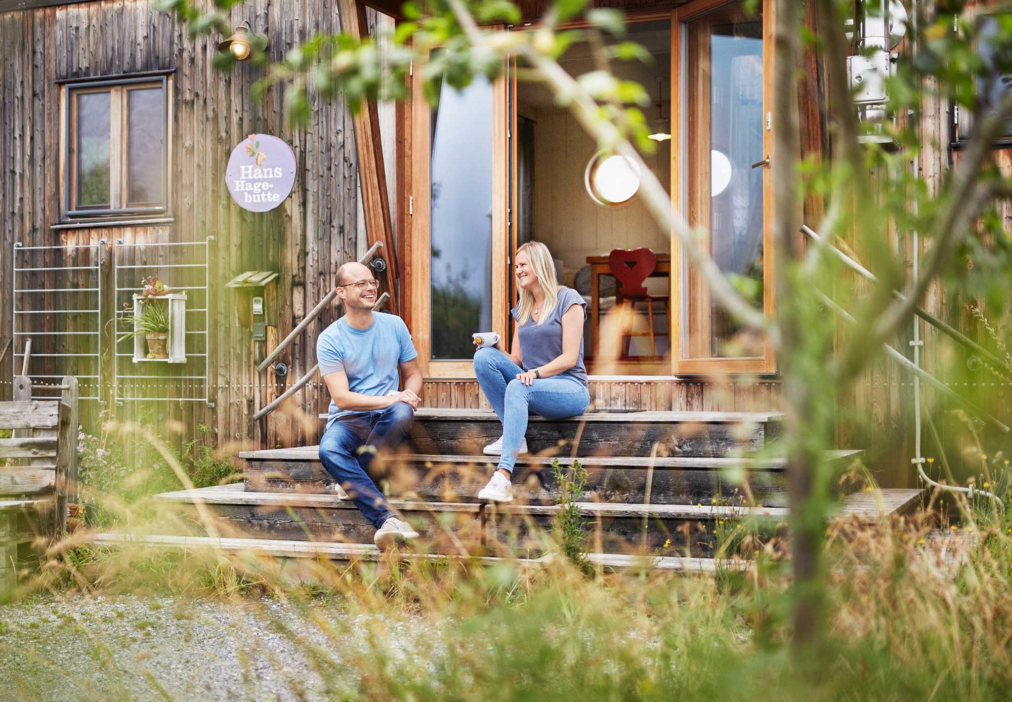Pärchen sitzt entspannt auf den Holzstufen vor dem Land Loft Hans Hagebutte