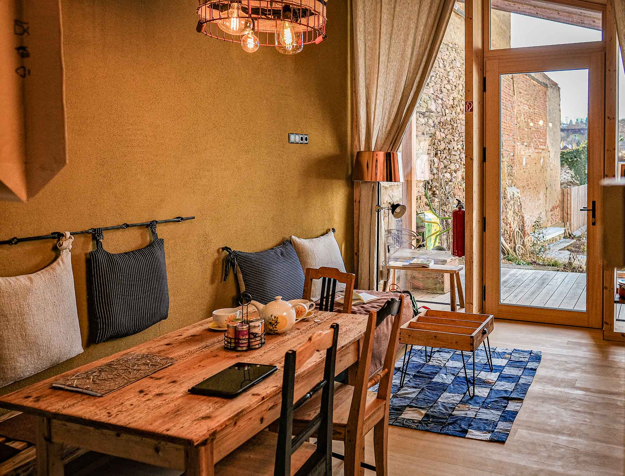 Rustikales Loft-Interieur mit Lehmwand, Holztisch und Blick auf den Innenhof