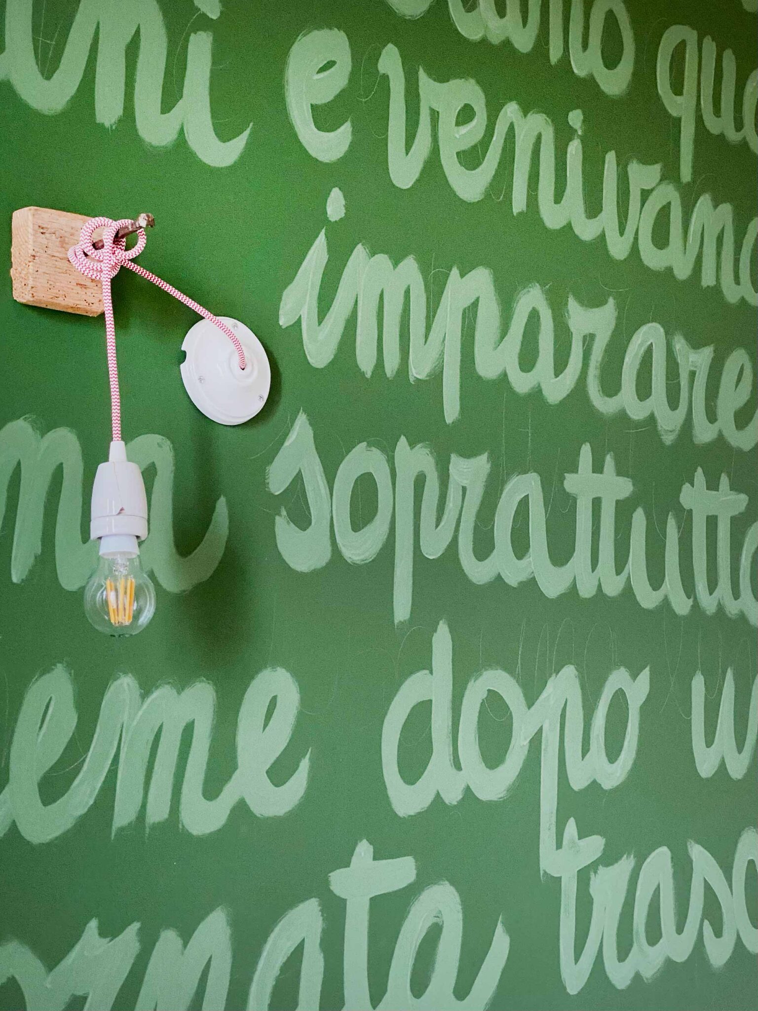 Handgemalter italienischer Wandspruch in Grüntönen mit Vintage-Lampe an Holzhalterung, Detailaufnahme im B&B La Scuola
