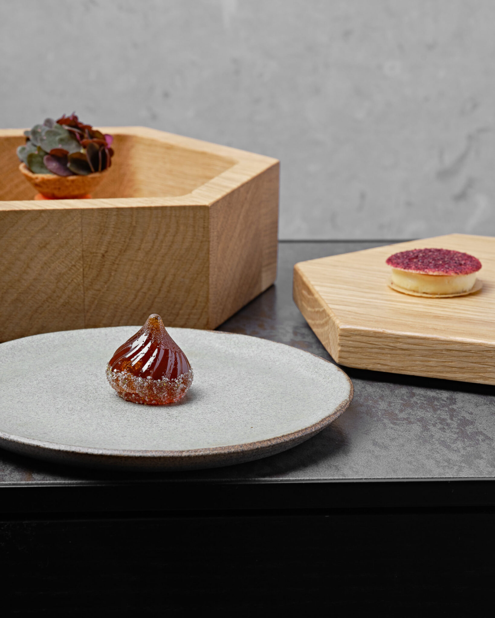 Drei kunstfertig angerichtete Petit-Fours auf Keramikteller und Holzplatten im Restaurant des Boutique Hotels Milka in Kranjska Gora