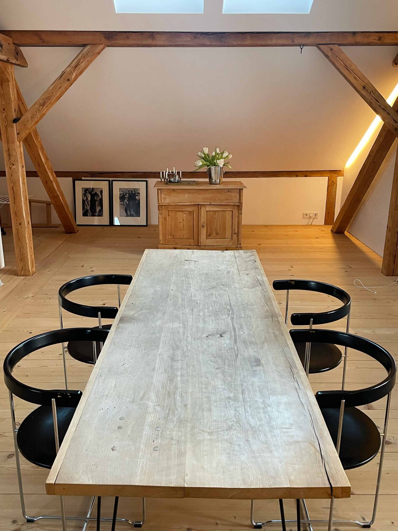 Esszimmer im Loft der Ferienwohnung Moosham13 mit großem Holztisch, schwarzen Designstühlen und freiliegenden Dachbalken