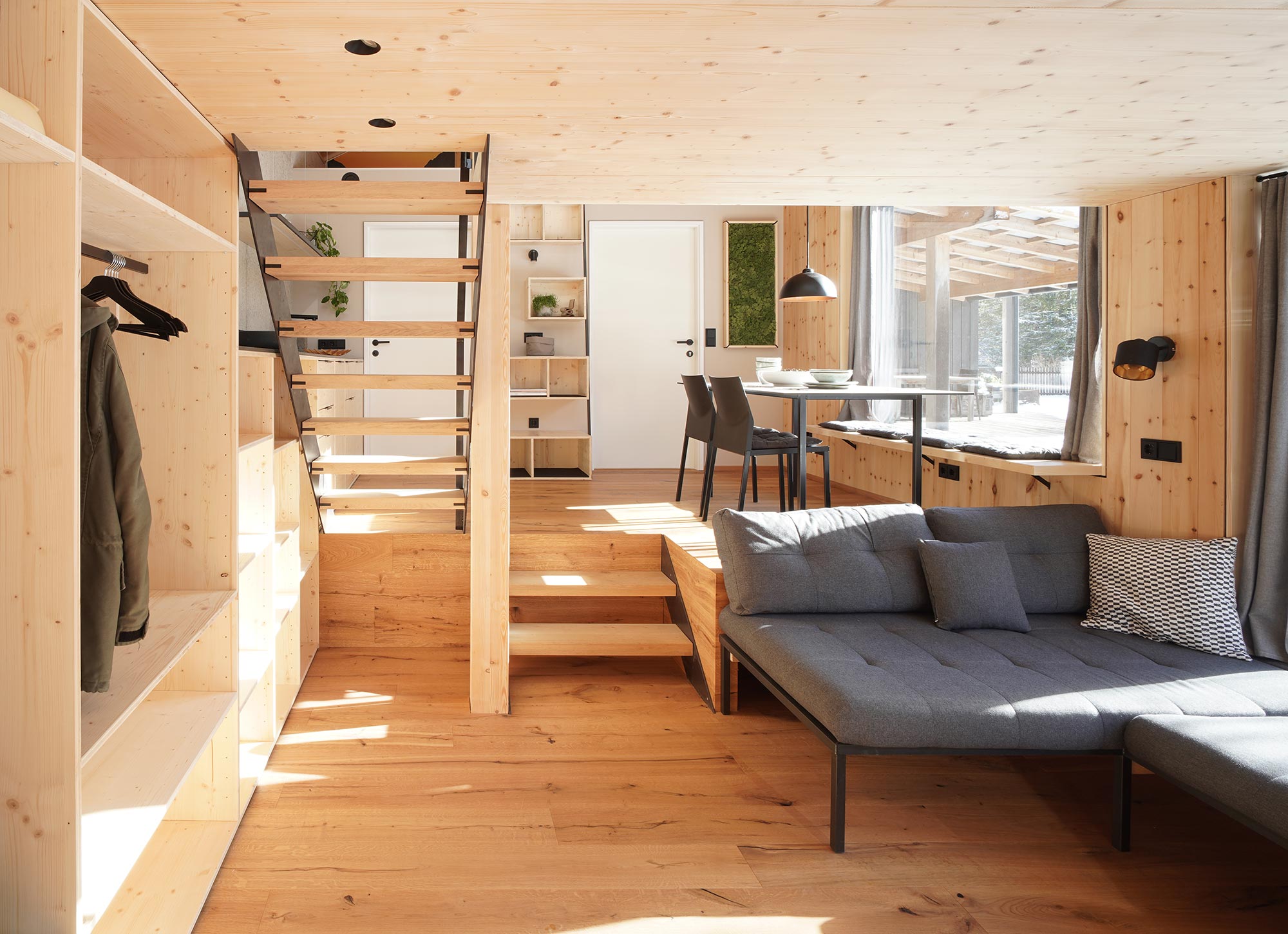 Sonnendurchfluteter Essbereich im Flussbett Ferienunterkunft mit freiliegenden Holzbalken, Satteldach und einem freischwebenden Regalmodul aus Holz zwischen zwei weißen Türen