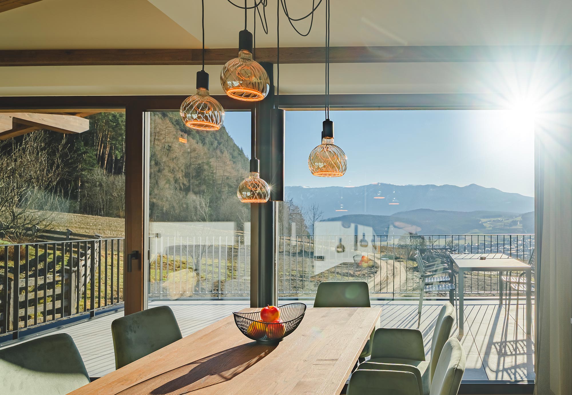 Heller Essbereich der Mountain Trattoria im Perntal Retreat mit großem Panoramafenster, Blick auf die schneebedeckten Südtiroler Berge, Holztisch und Hängeleuchten aus Glas