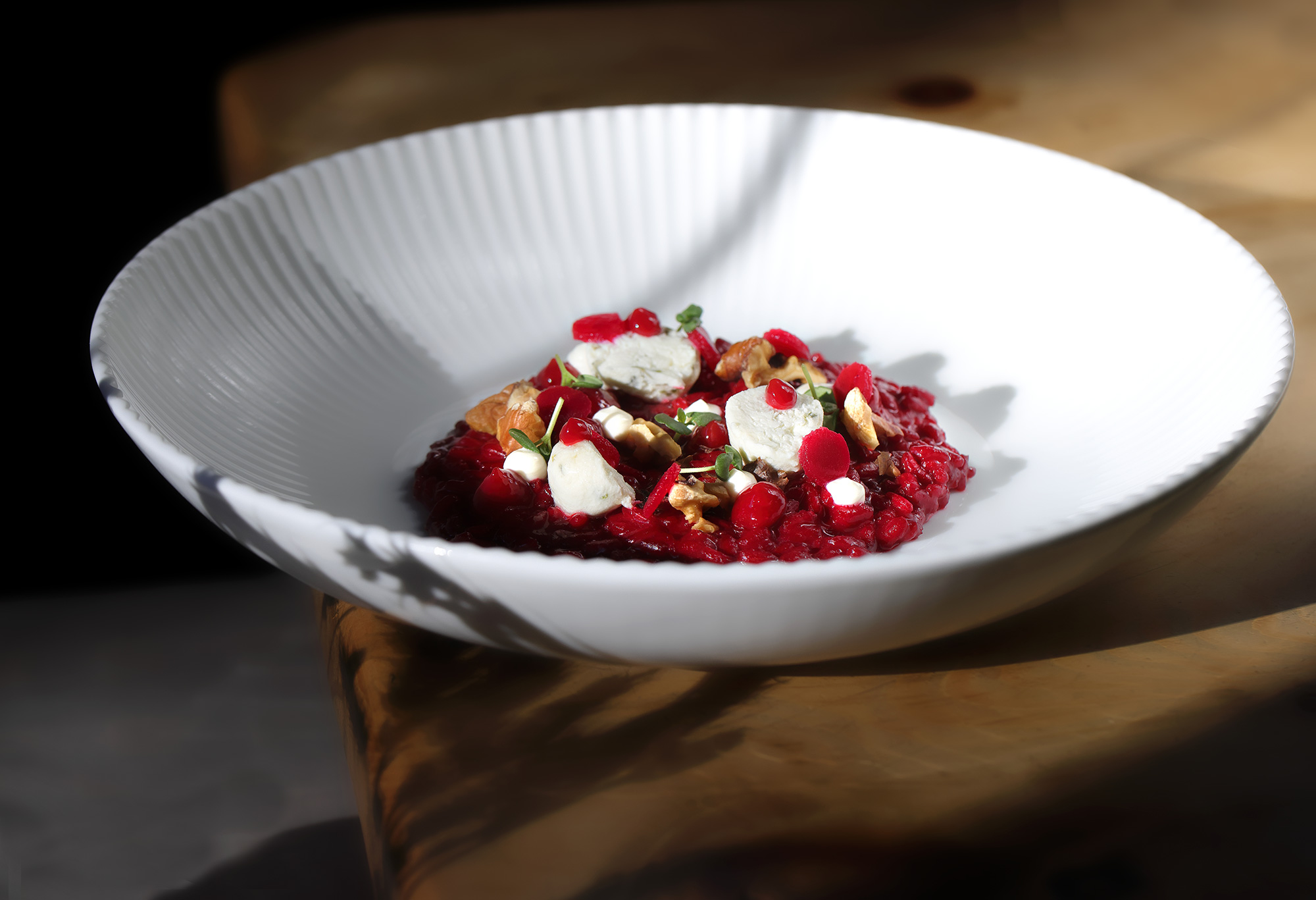 Teller mit Rote-Bete-Risotto, Ziegenkäse, Walnüssen und Granatapfelkernen aus der Mountain Trattoria des Perntal Retreats in Gais, Südtirol