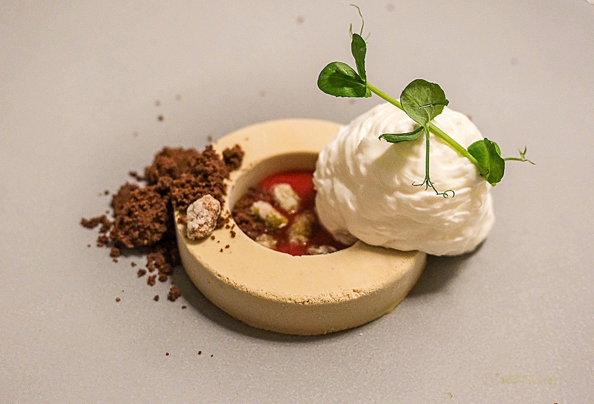 Kunstvolles Dessert im Restaurant des Stroblhof Eppan: Törtchen mit Erdbeerfüllung, Sahnehaube, Kakaokrümeln und Erbsensprossen