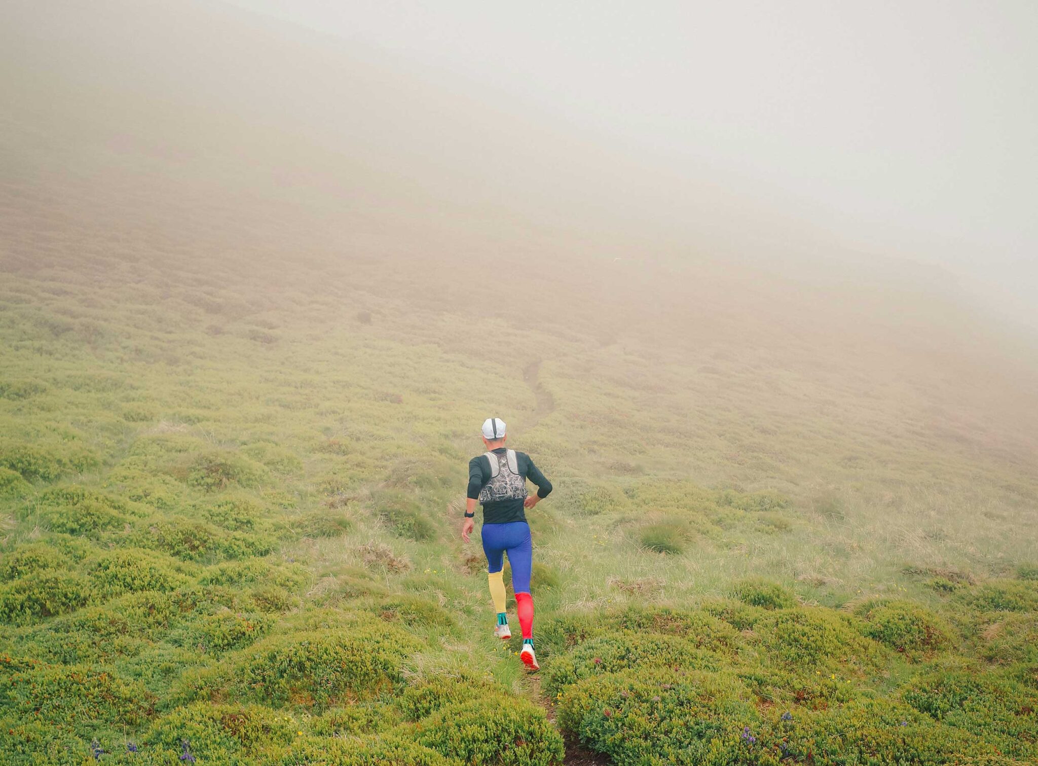 Trailrunner läuft durch Nebel auf schmalen Bergpfad – Good Travel Blog