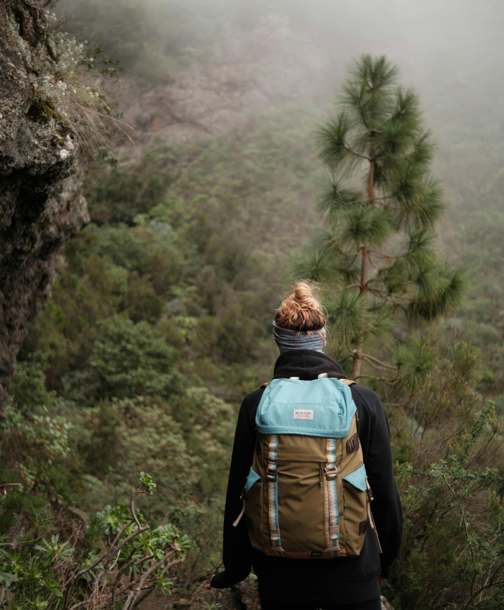 Wanderin mit Rucksack blickt in nebelbedecktes Bergtal – Good Travel Blog