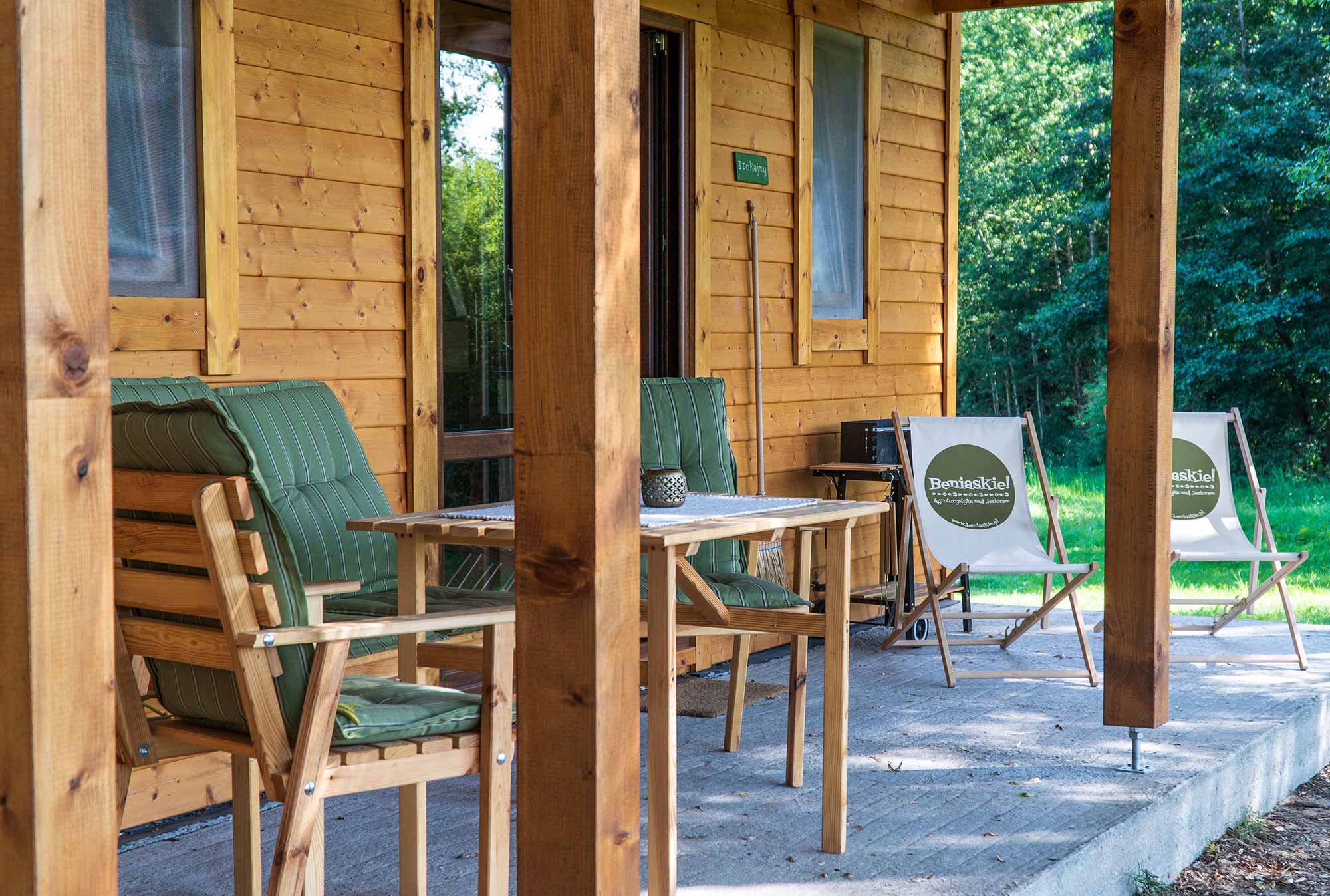 Überdachte Holzveranda mit gestreiften Sesseln und Liegestühlen im Agriturismo Beniaskie!, Bieniasze, Ermland-Masuren