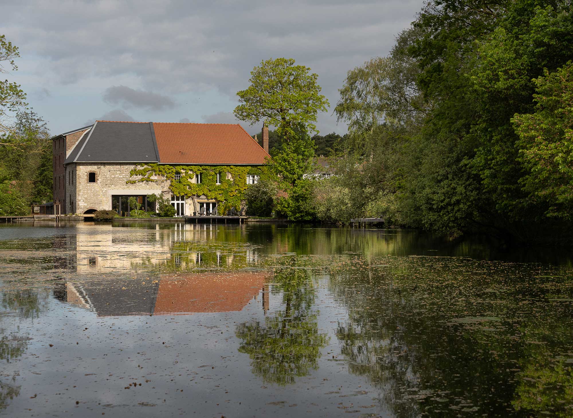 Historische Mühle des B&B Moulin Moulin in Dannes, Hauts-de-France, spiegelt sich im Teich
