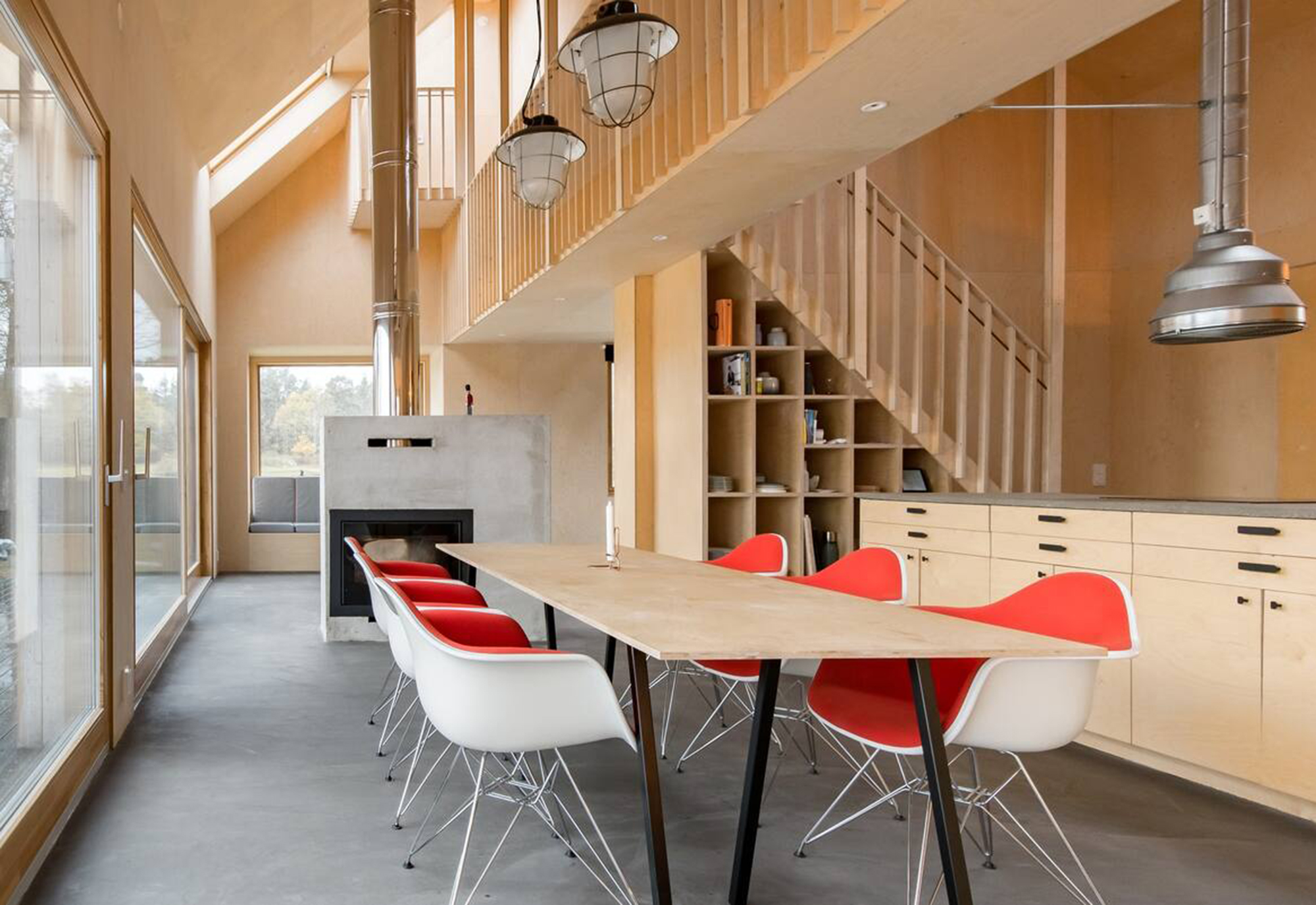 Essbereich mit langem Holztisch, roten Stühlen und offenem Kamin im Ferienhaus Goda, Skälvik