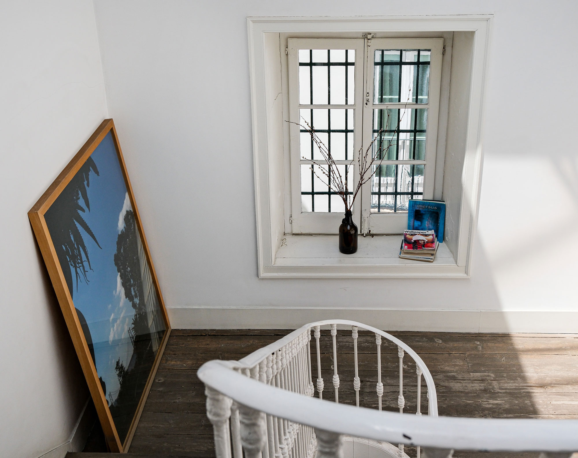 Treppenabsatz mit altem Sprossenfenster und gerahmtem Kunstwerk im Baixa House, Lissabon