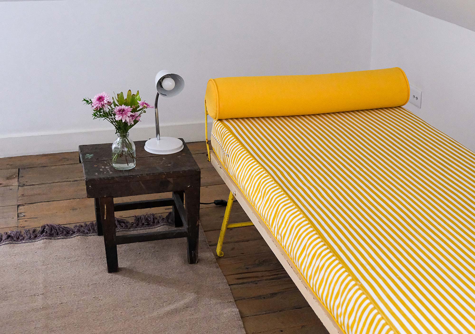 Gelb gestreiftes Daybed mit Beistelltisch und Blumenstrauß im Baixa House, Lissabon