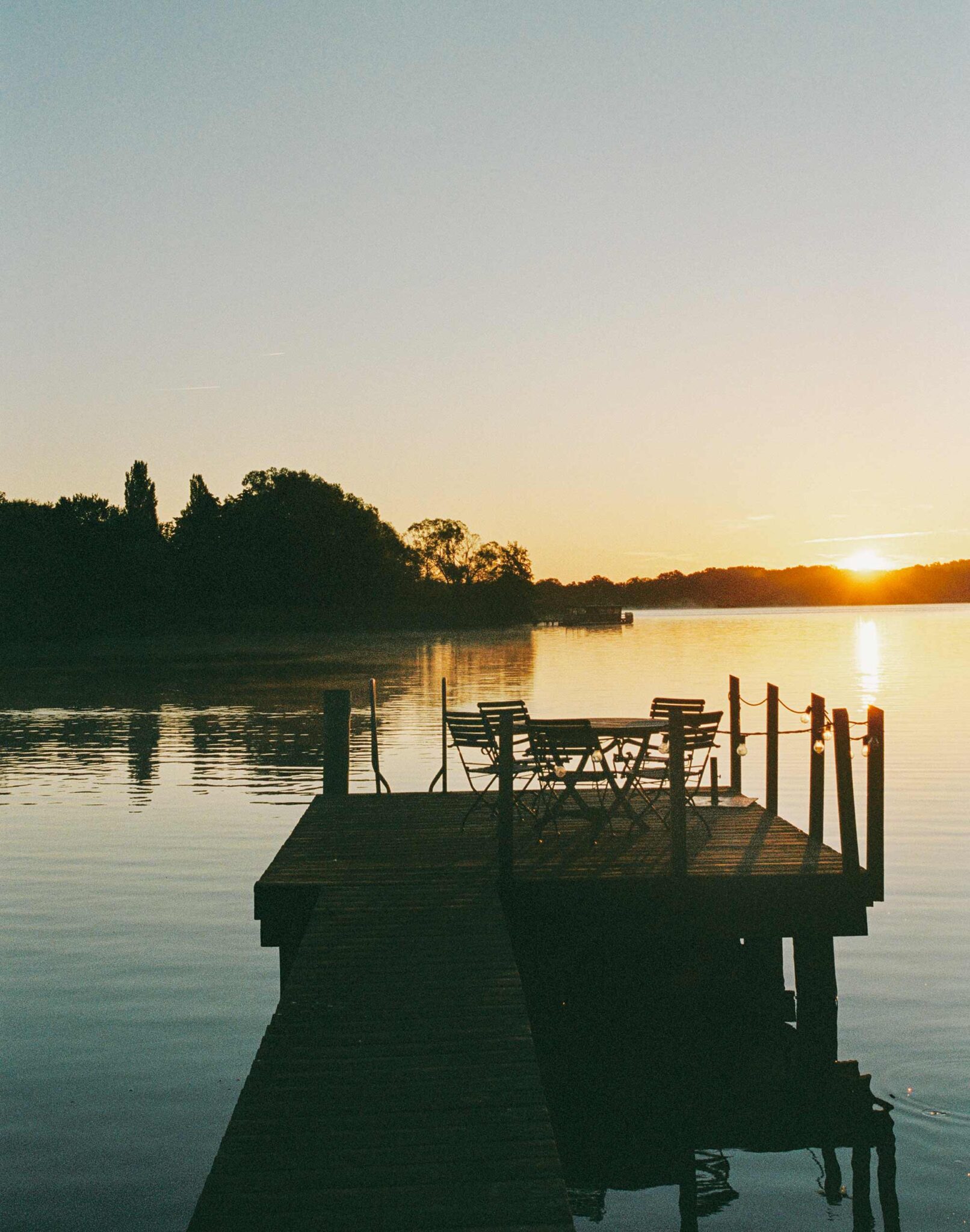 Steg mit Tisch und Stühlen bei Sonnenuntergang an der Havel, Ferien Werder Scheunhornweg