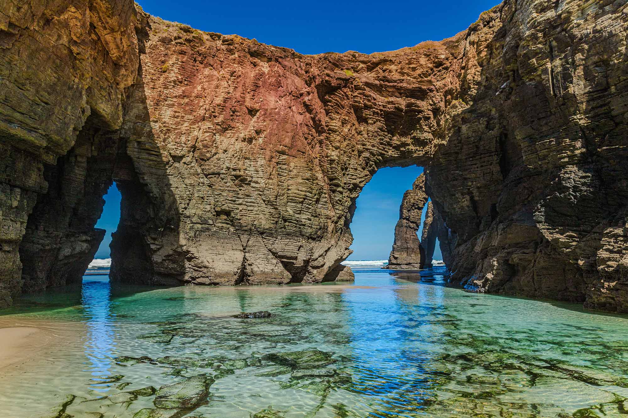 Praia das Catedrais in Galizien mit begehbaren Felsbögen und türkisfarbenem Wasser bei Ebbe