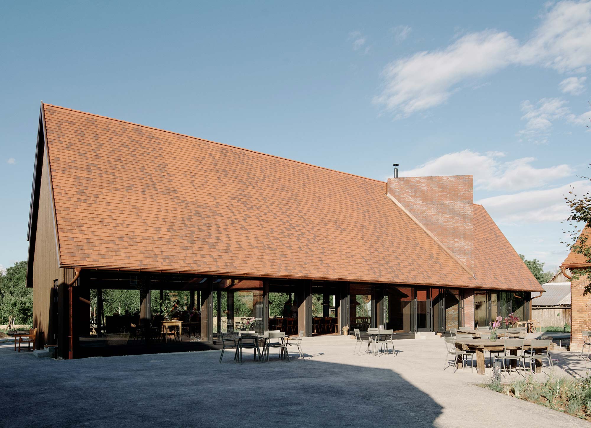 Landwirtschaftliches Gebäude mit rotem Ziegeldach und Terrasse auf der Michelberger Farm in Vetschau