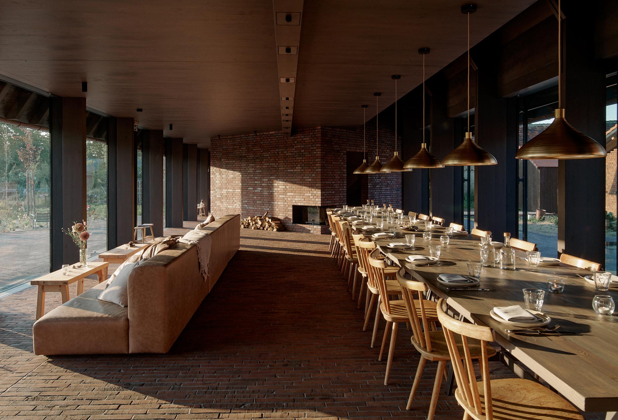 Langer Holztisch mit gedeckten Plätzen und Kamin im Restaurant der Michelberger Farm