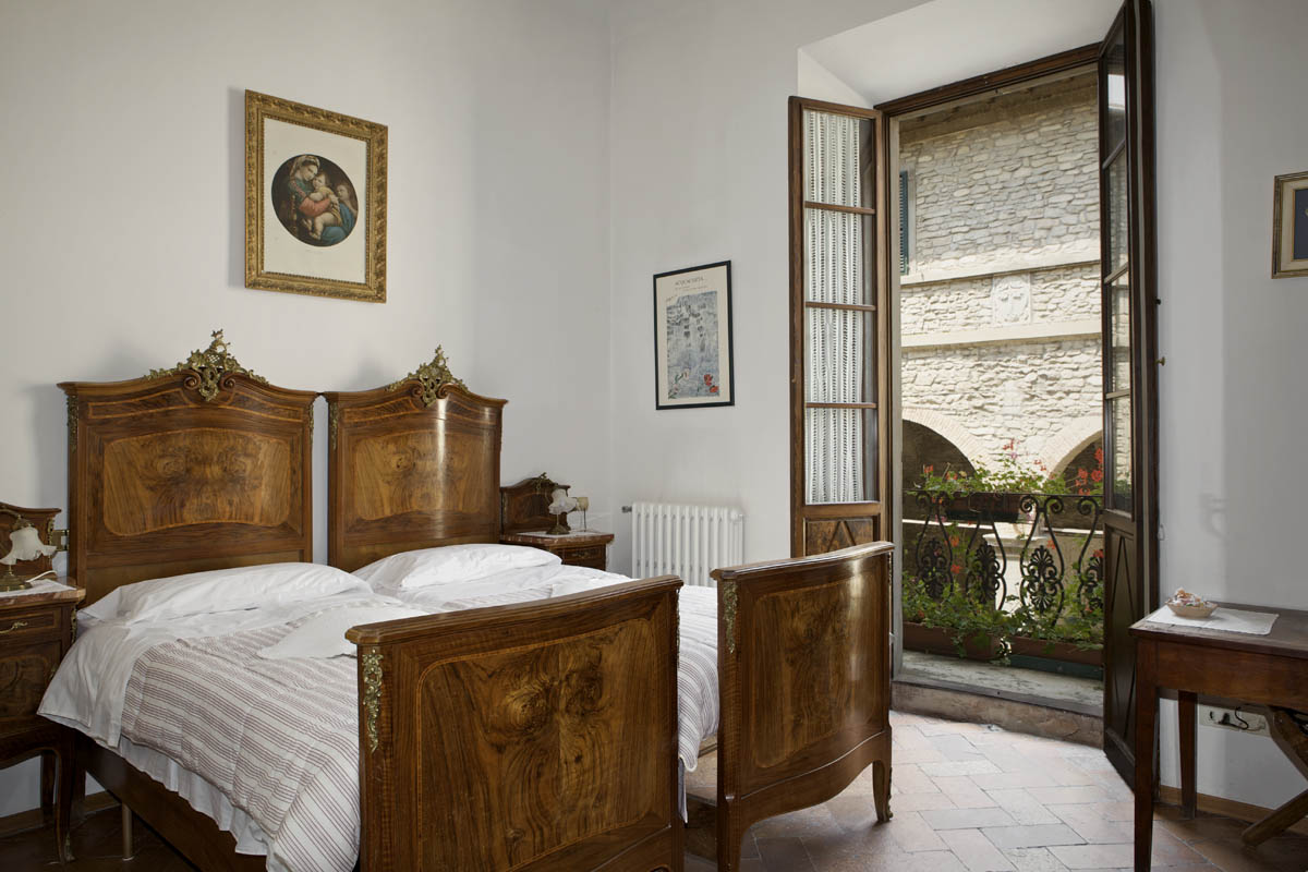 Gästezimmer mit antiken Betten und Balkon in einem Haus des Albergo Diffuso Al Vecchio Convento