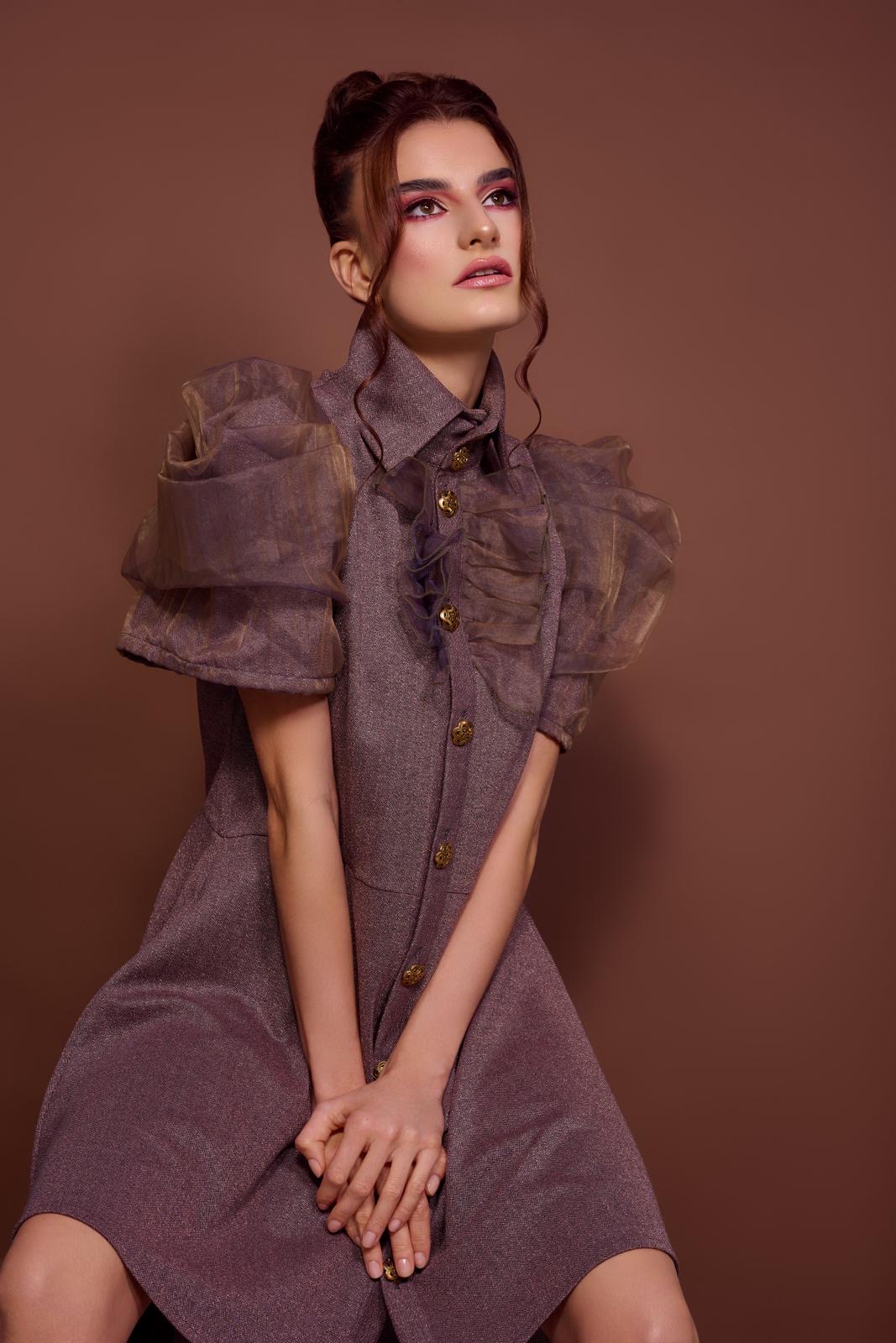 Model in malvenfarbenem Kleid mit Puffärmeln aus Organza und goldenen Knöpfen, Design von Angelika Kauffmann
