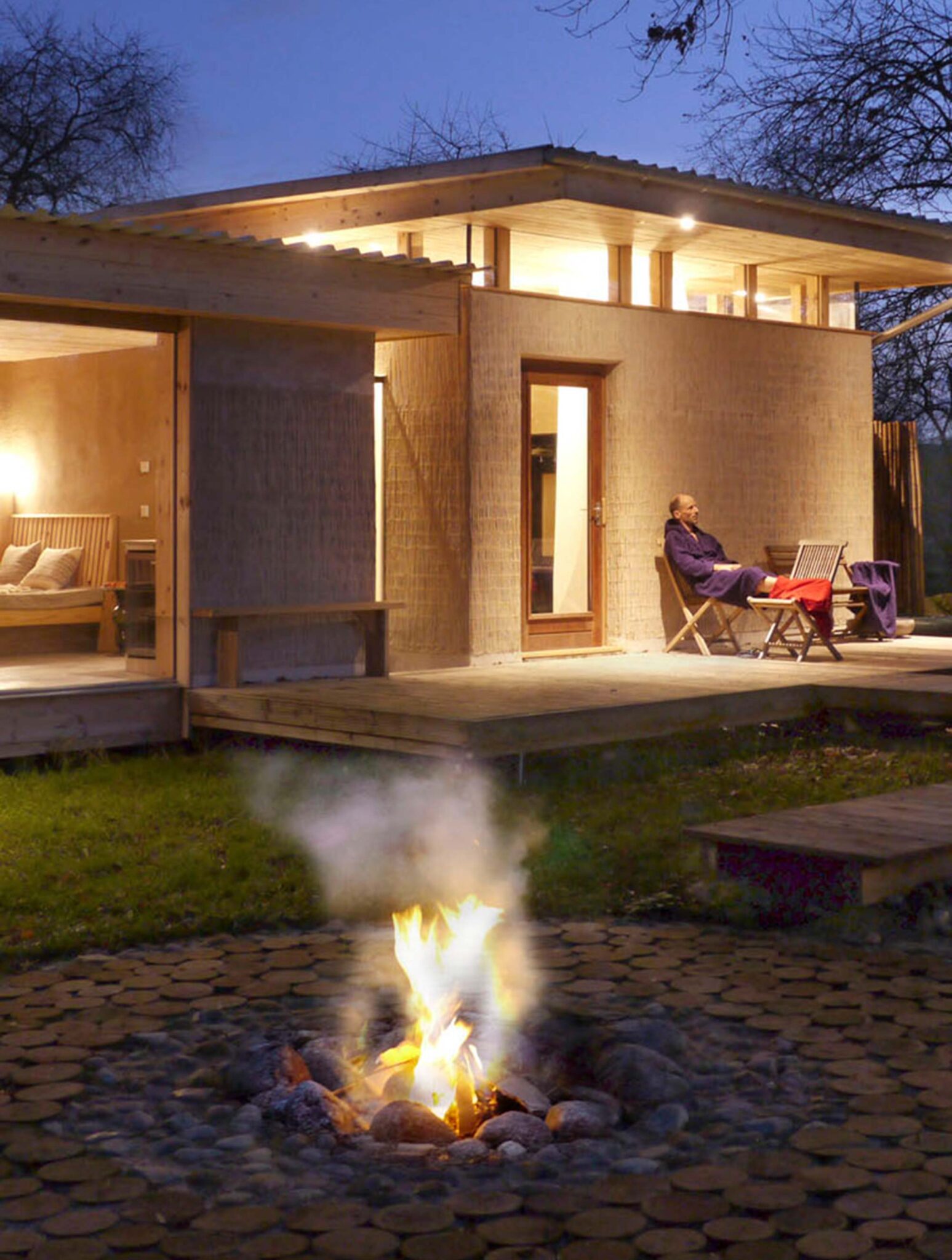 Sauna-Haus mit Lagerfeuer und Terrasse am Abend im Re:hof Rutenberg in Lychen, Brandenburg