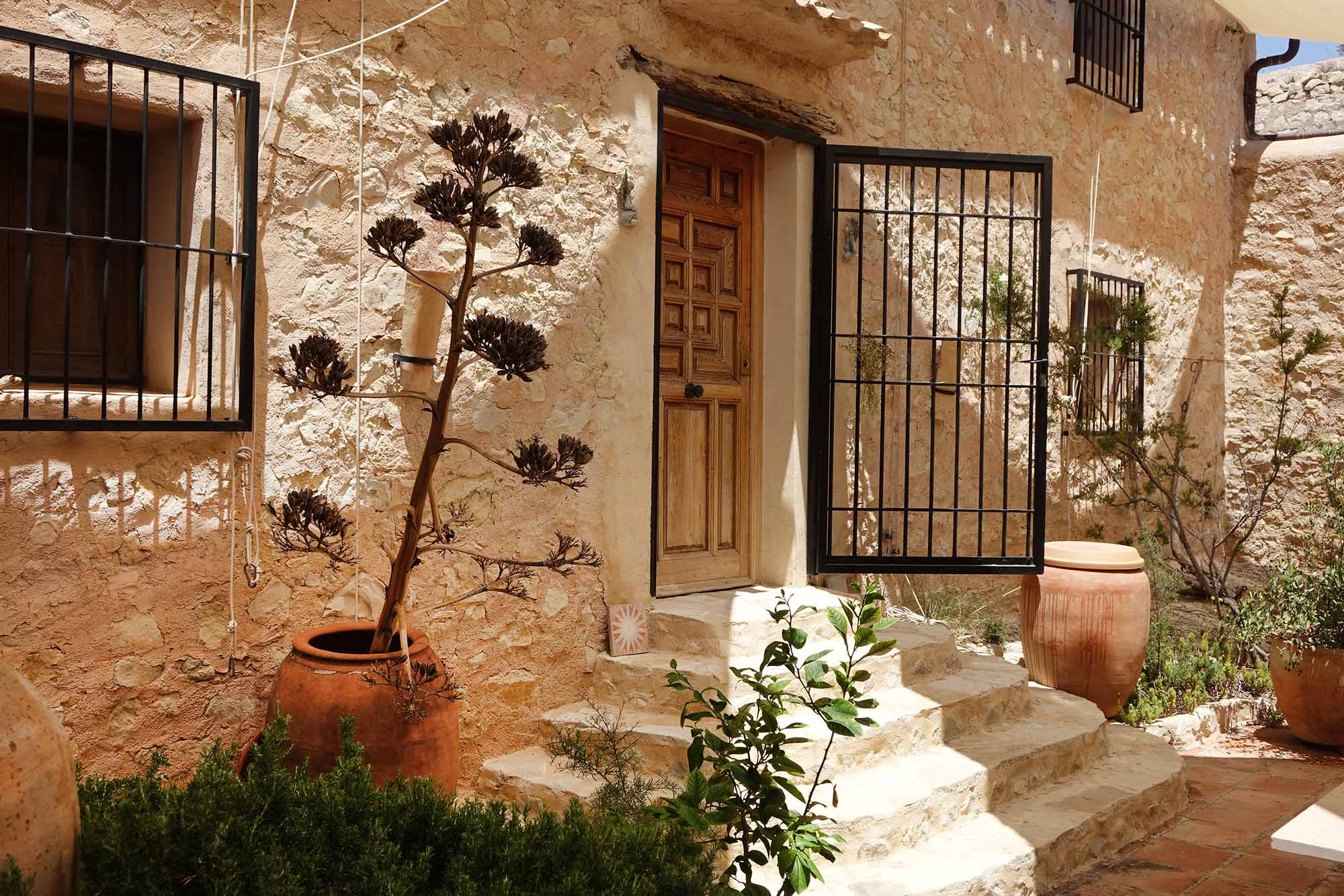 Steinfassade mit schmiedeeisernen Türen und Terrakottatöpfen an der Finca Foyeta, Costa Blanca