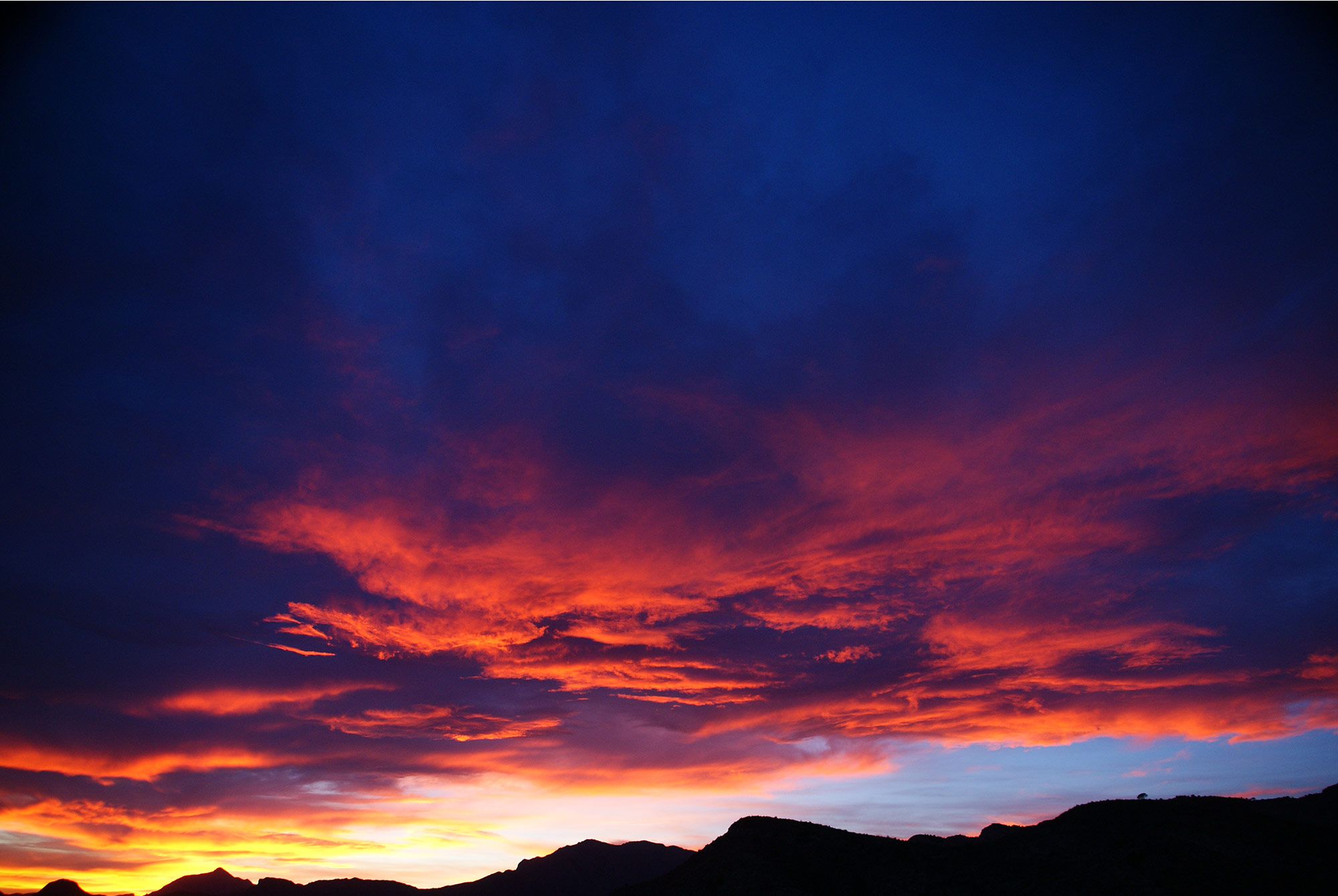 Dramatischer Sonnenuntergangshimmel in Orange und Blau über den Bergen der Costa Blanca
