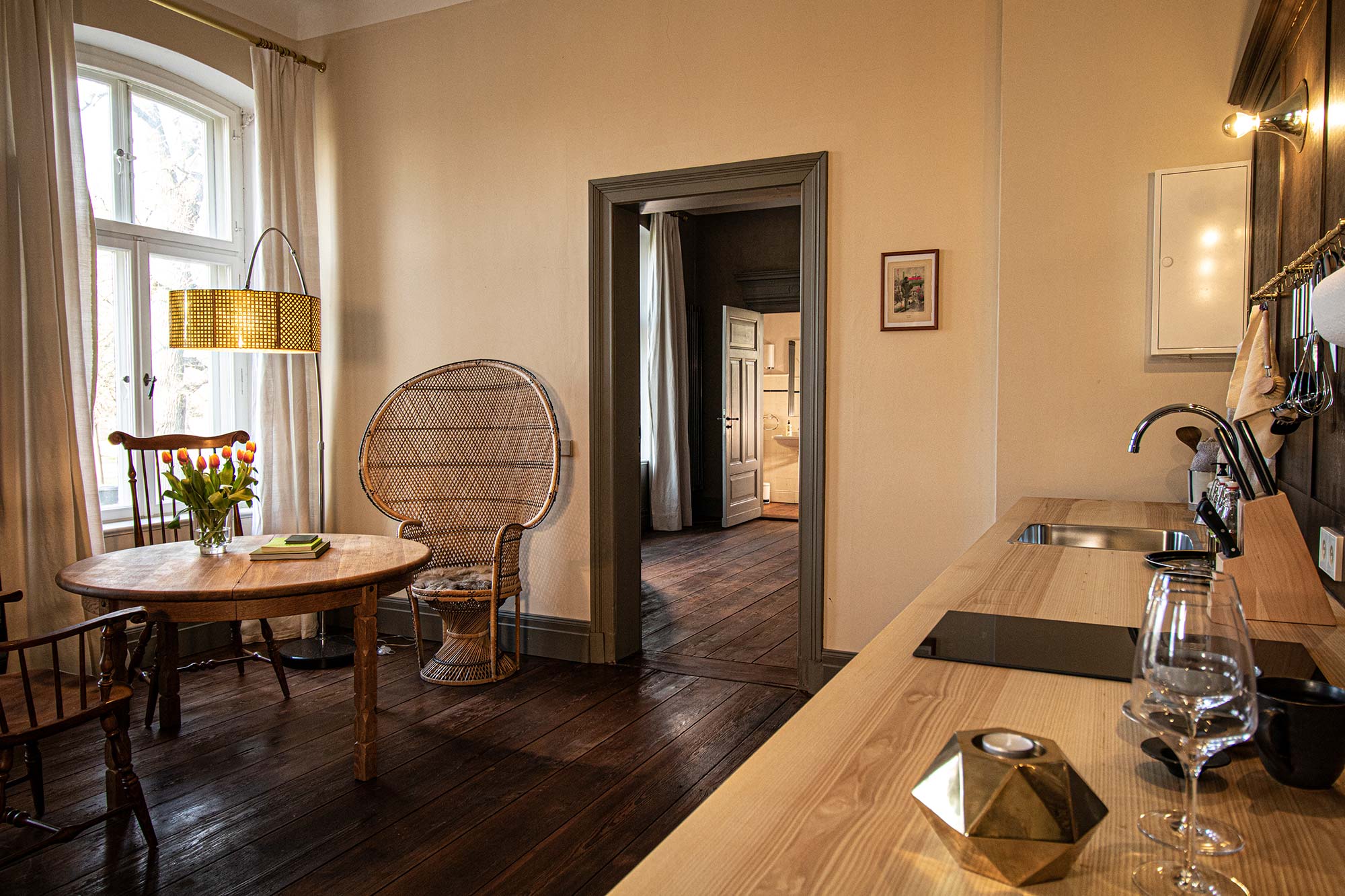 Gemütliches Zimmer mit Rattansessel und rustikalem Holztisch im Gutshaus Zarchlin, Mecklenburgische Seenplatte