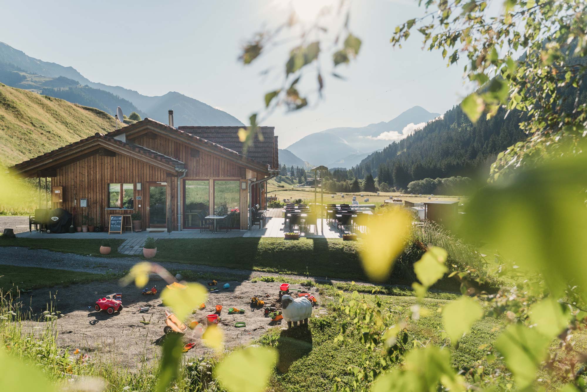 Holzhütte des Naturcamping Viva mit Bergpanorama und Spielplatz in Graubünden, Schweiz