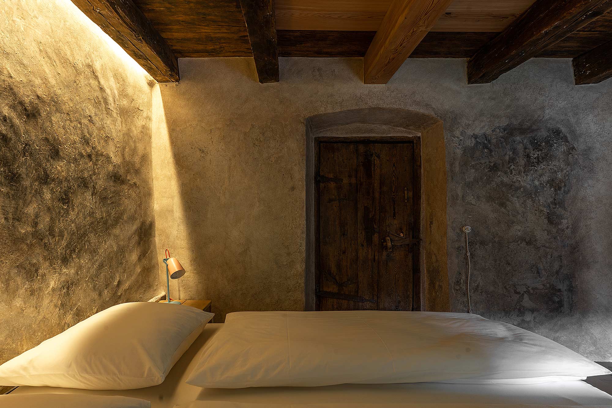 Rustikales Zimmer mit Steinwänden und alter Holztür im Hof Unternberg, Südtirol