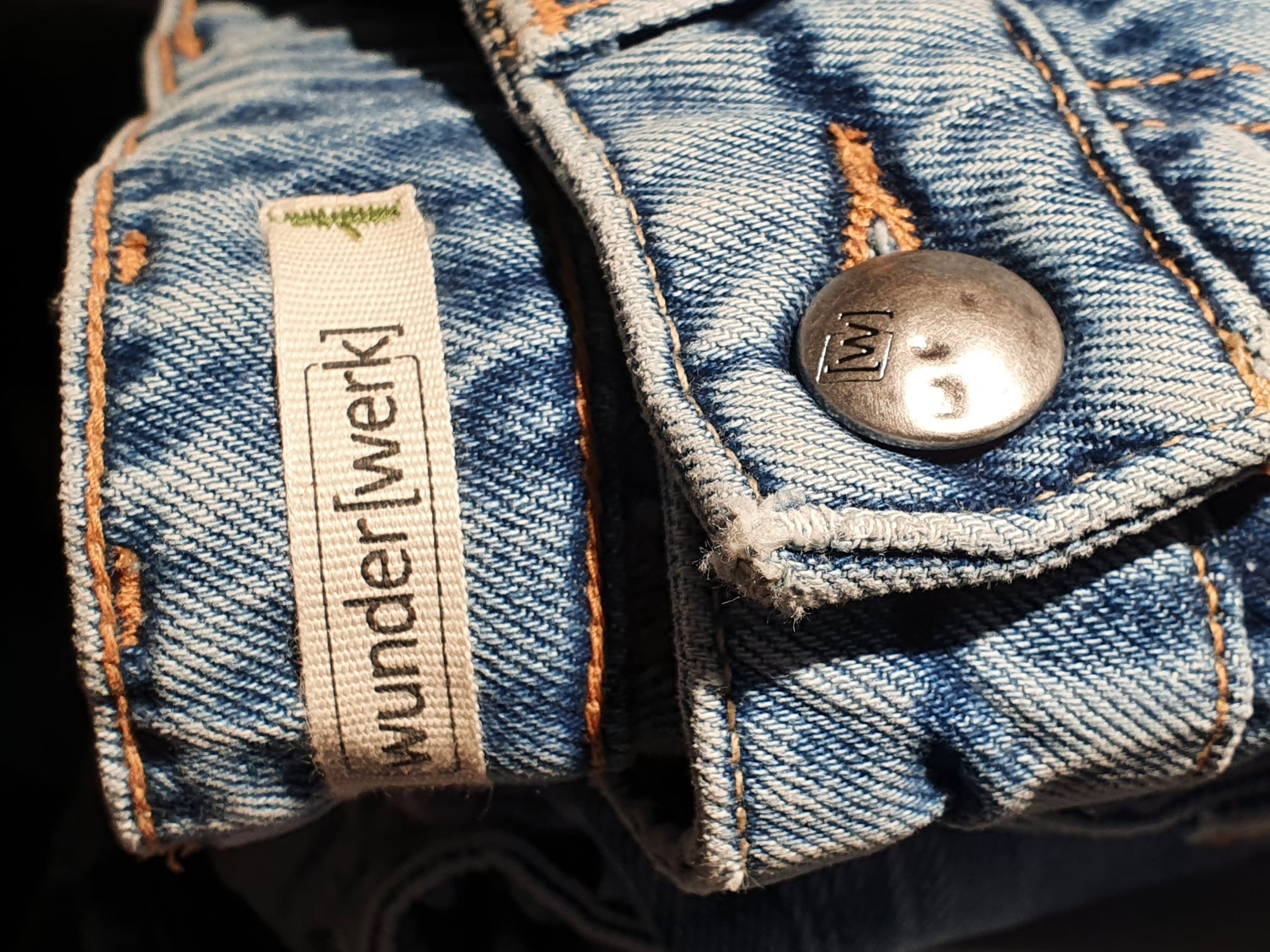 Nahaufnahme des wunderwerk-Labels und Knopfdetails an einer Jeans