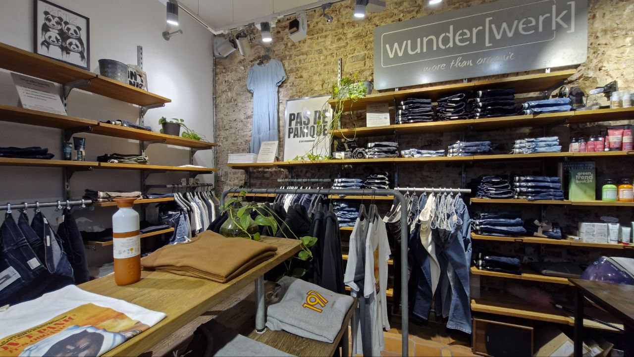Innenansicht des wunderwerk-Ladenlokals mit Jeans-Regalen, Kleidung und Logo-Schild Bildunterschrift: Der wunderwerk-Store in Düsseldorf zeigt die Kollektion der Modemarke vor Ort.