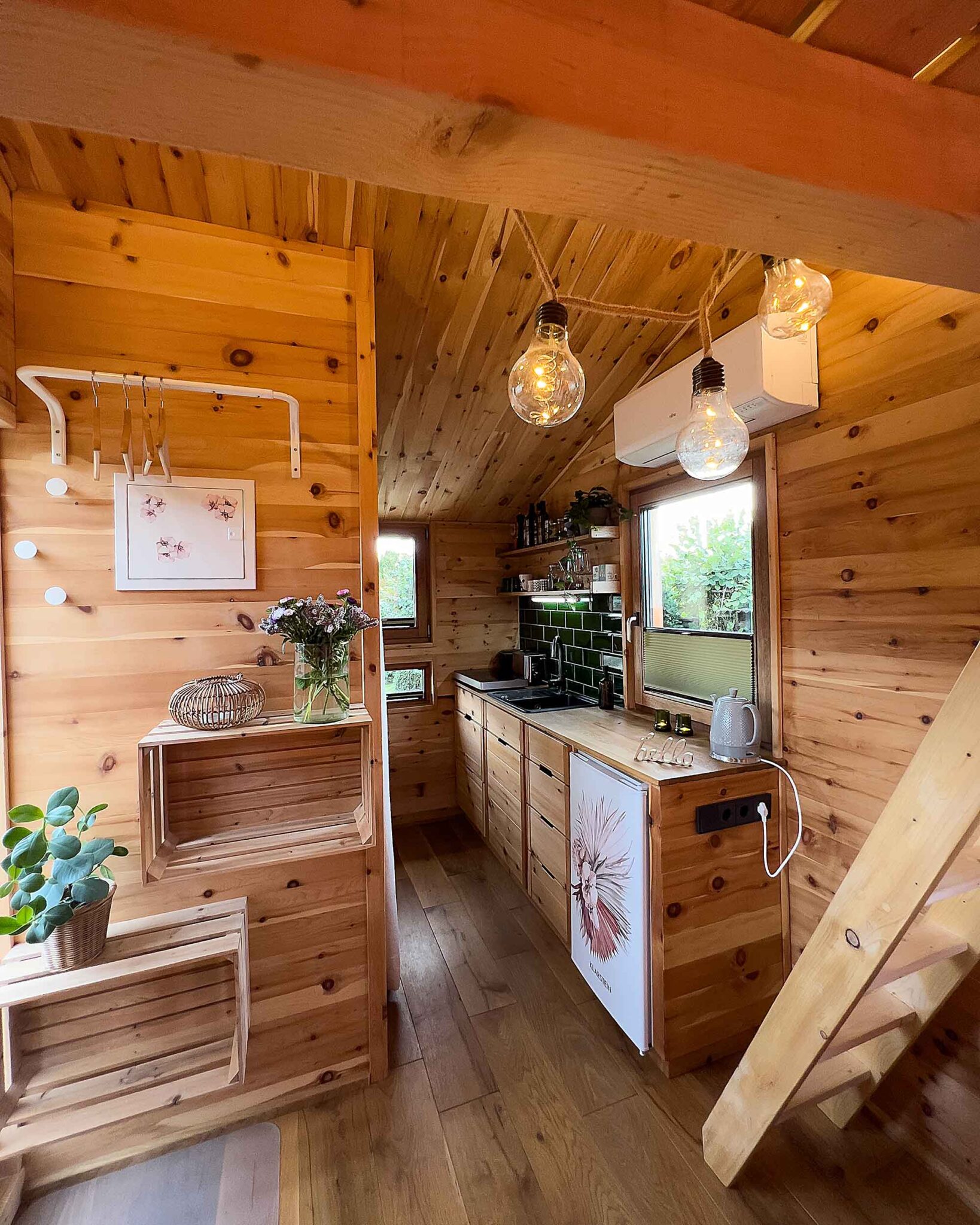 Gemütlicher Innenraum des Tiny House Ferienhauses Waldhauszeit mit Holzverkleidung, Küchenzeile und Lichterkette