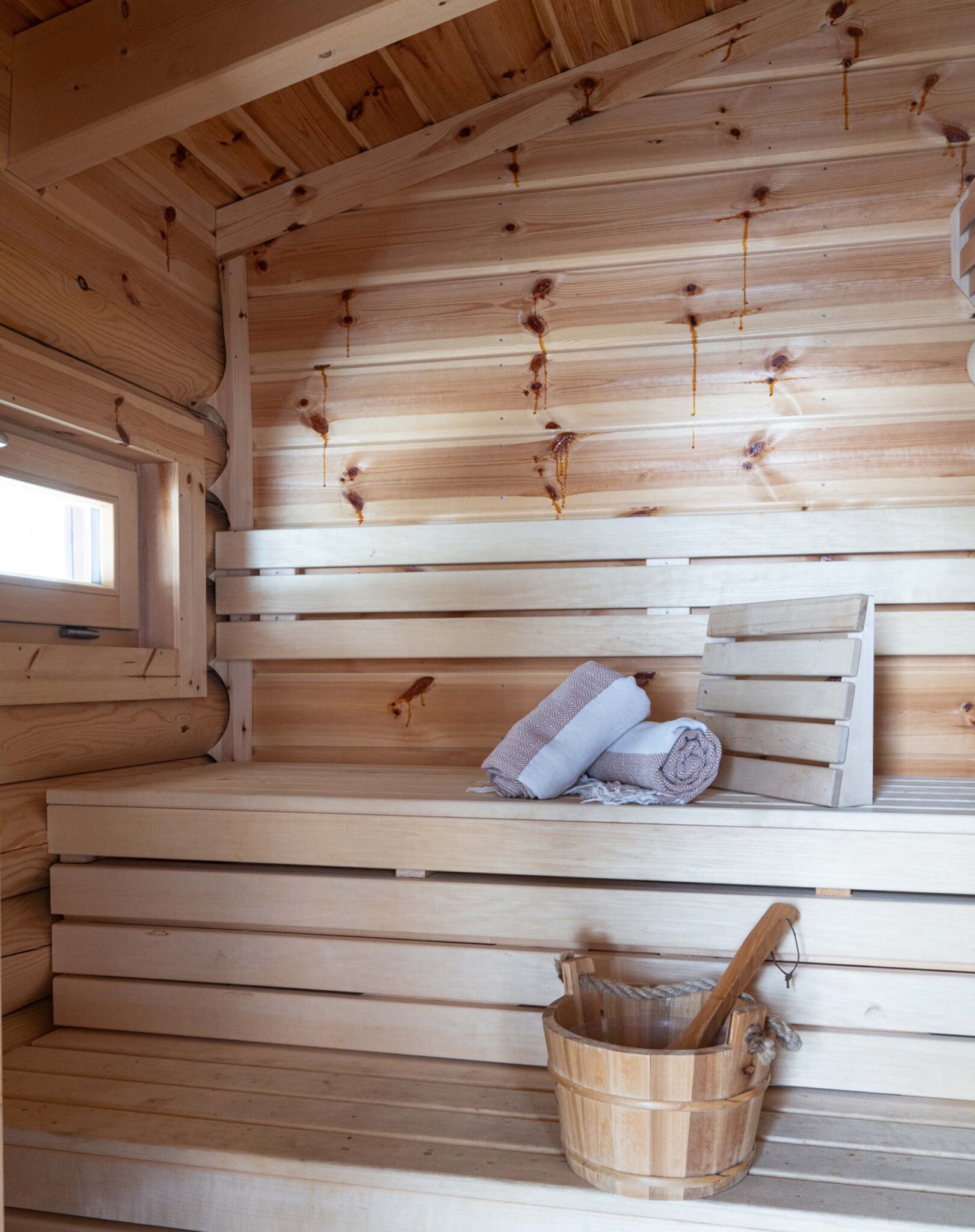 Holzsauna der Hütte am Wald mit Sitzbänken, aufgerollten Handtüchern und Saunazubehör