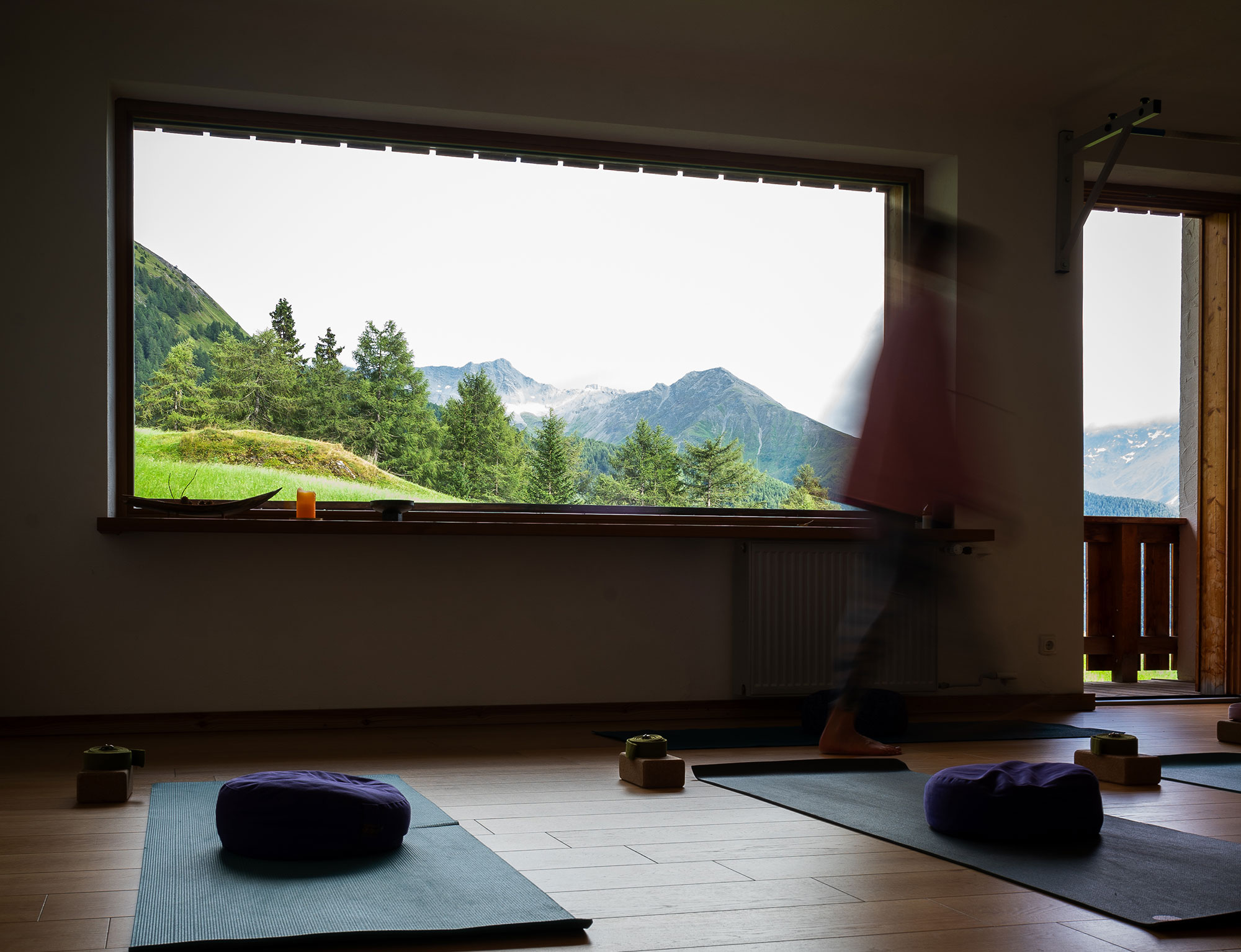 Yogaraum der MoaAlm Mountain Retreat mit Matten, Meditationskissen und großem Panoramafenster zu den Bergen