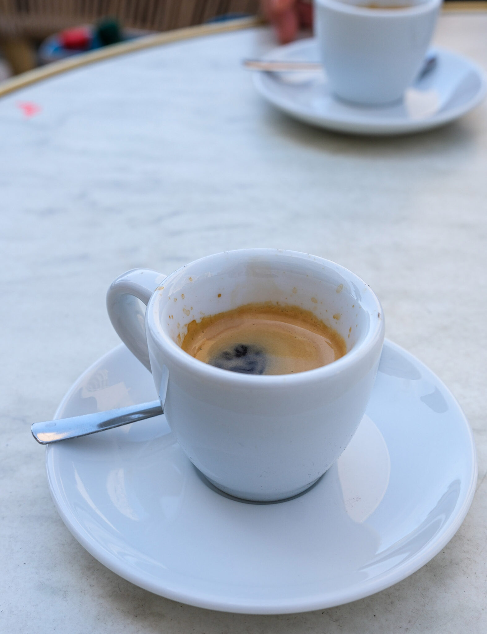 Espresso in weißer Tasse auf einem runden Marmor-Bistrotisch in einem Café in Marseille