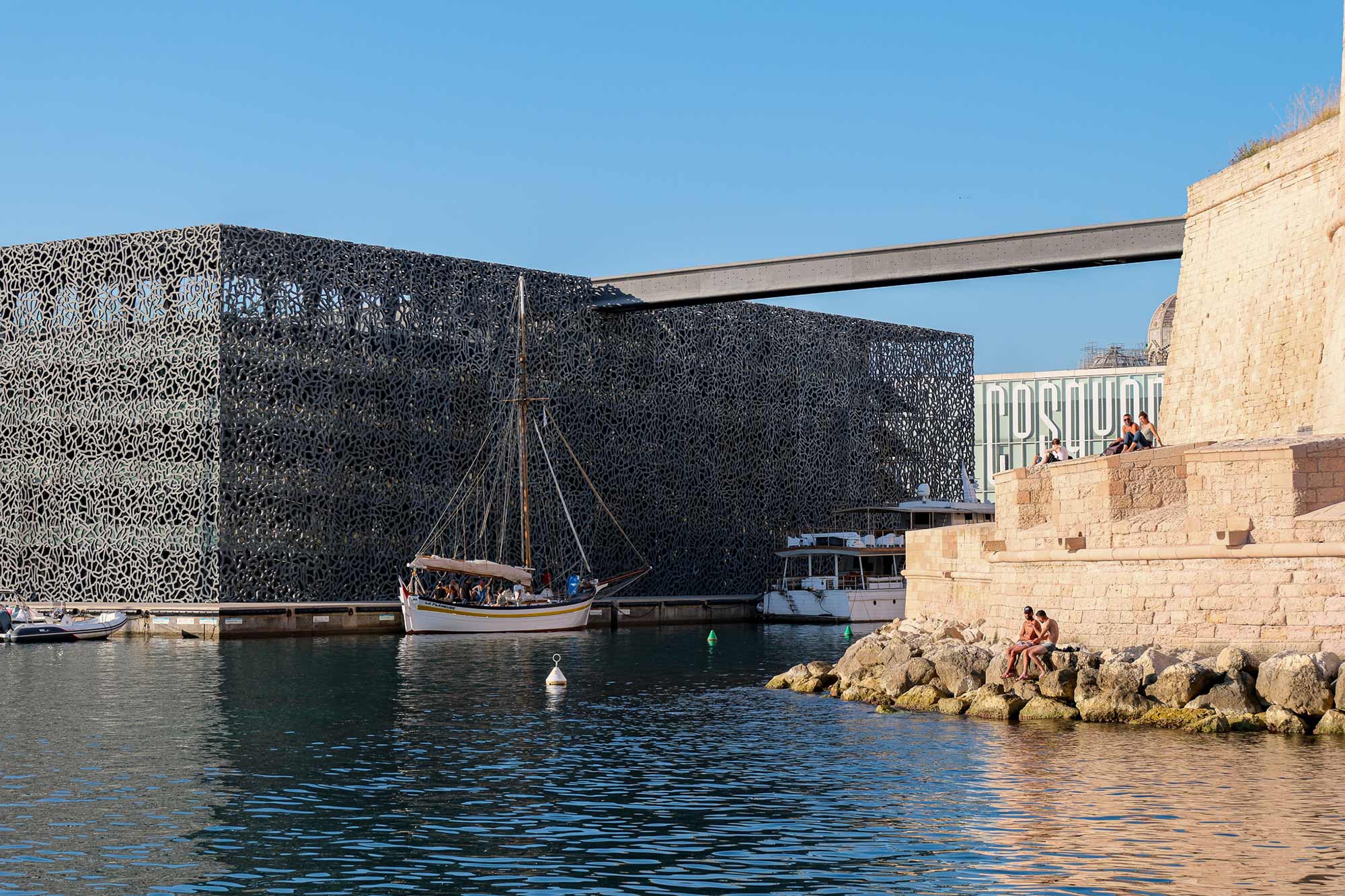 Traditionelles Segelboot vor der schwarzen Gitterfassade des Mucem neben dem Fort Saint-Jean am Hafen von Marseille