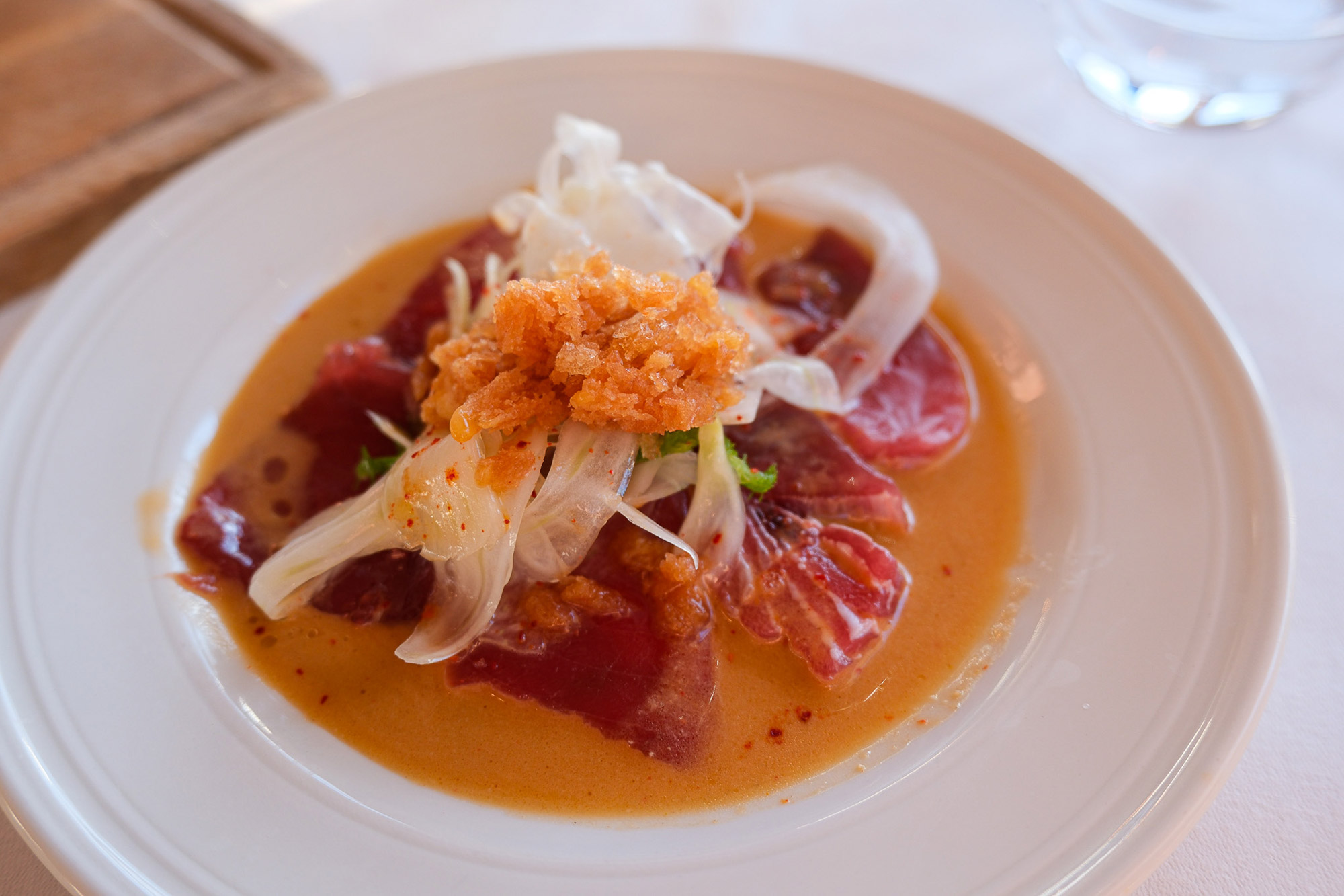 Roher Thunfisch mit hauchdünnem Fenchel, Granité und orangefarbener Sauce in einem tiefen Teller in Marseille