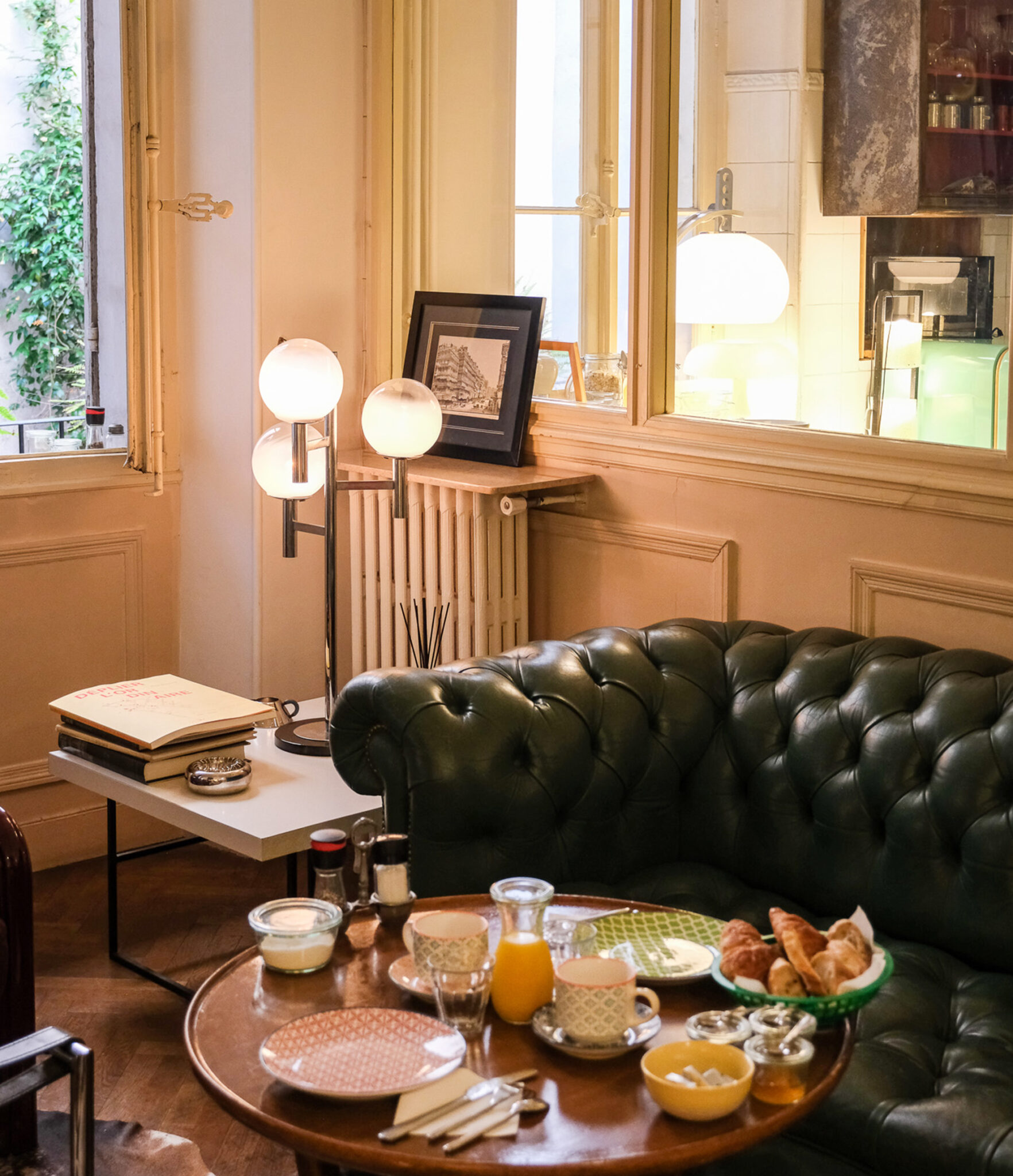 Gedeckter Bistrotisch mit Marmorplatte, Croissants, Baguette, Marmelade und Orangensaft vor petrolblauer Wandvertäfelung in der Pension Edelweiss in Marseille