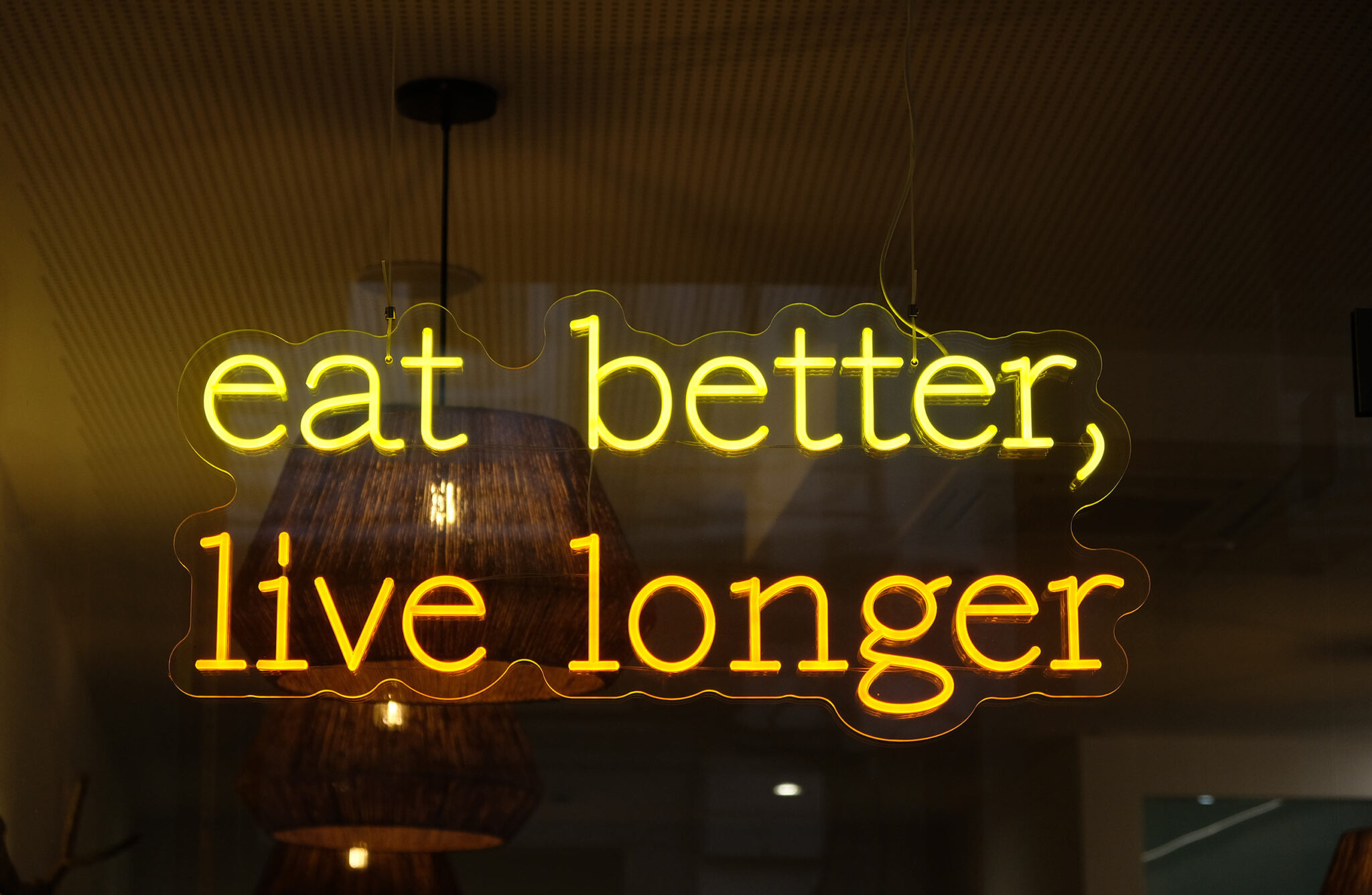 Gelbes Neonschild mit dem Spruch „eat better, live longer“ im Restaurant 360º by hygge&healthy in Viana do Castelo