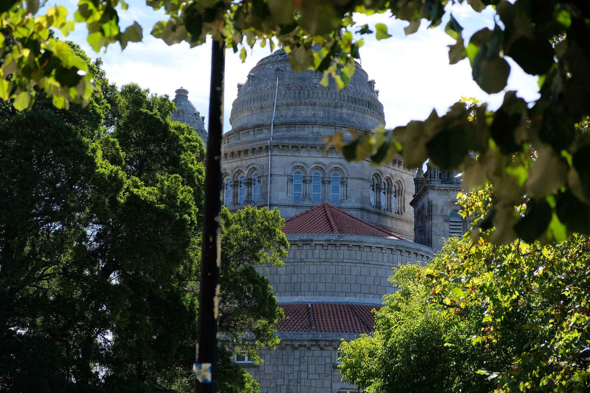 Kuppel der Basilika Santa Luzia in Viana do Castelo, eingerahmt von grünen Baumkronen