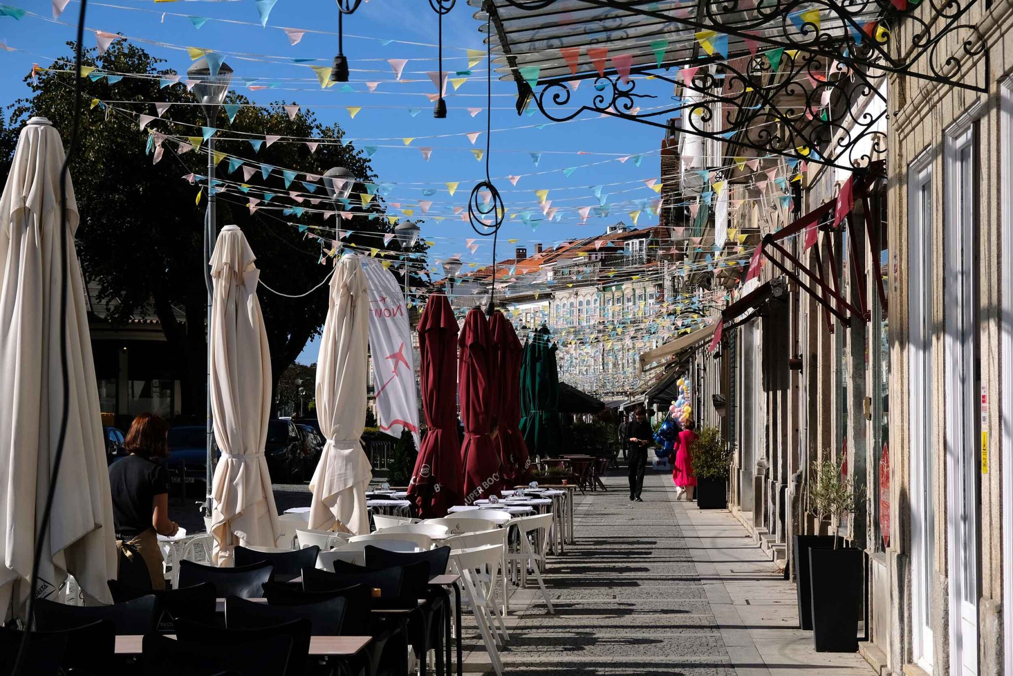 Straßencafés mit Sonnenschirmen unter bunten Wimpelgirlanden in der Altstadt von Viana do Castelo